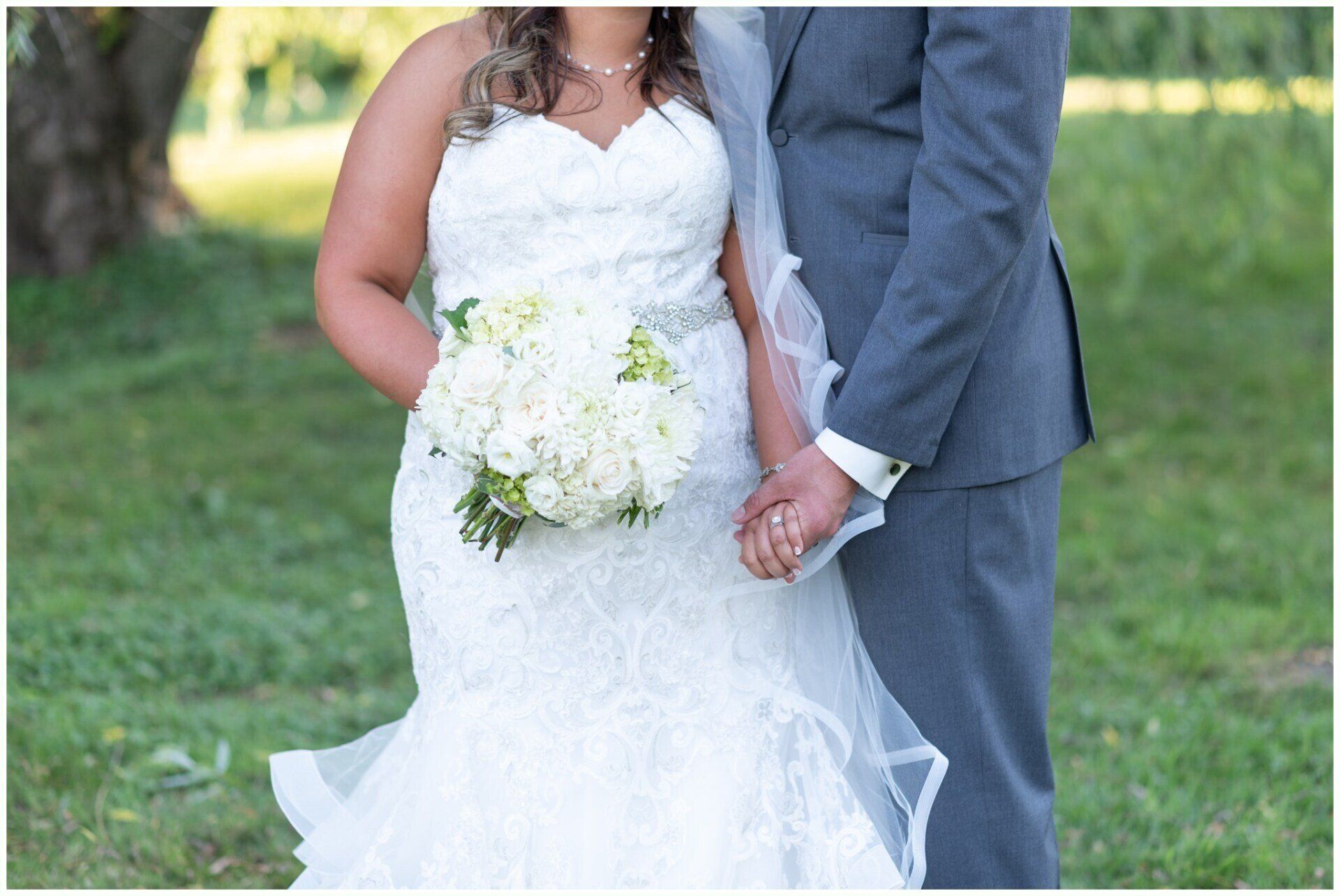 Bride and groom holding hands outdoors, with the bride in a white dress and bouquet