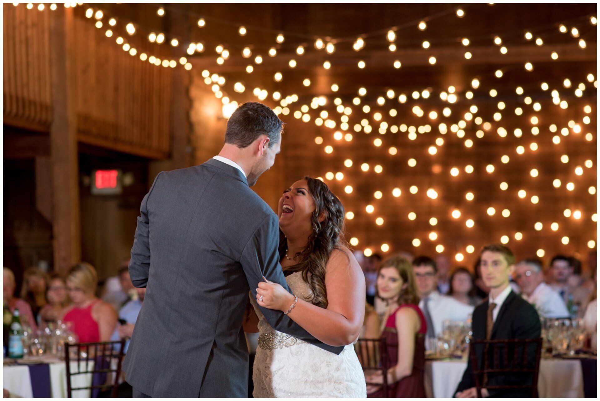 Bride and groom dancing at a wedding reception under warm string lights