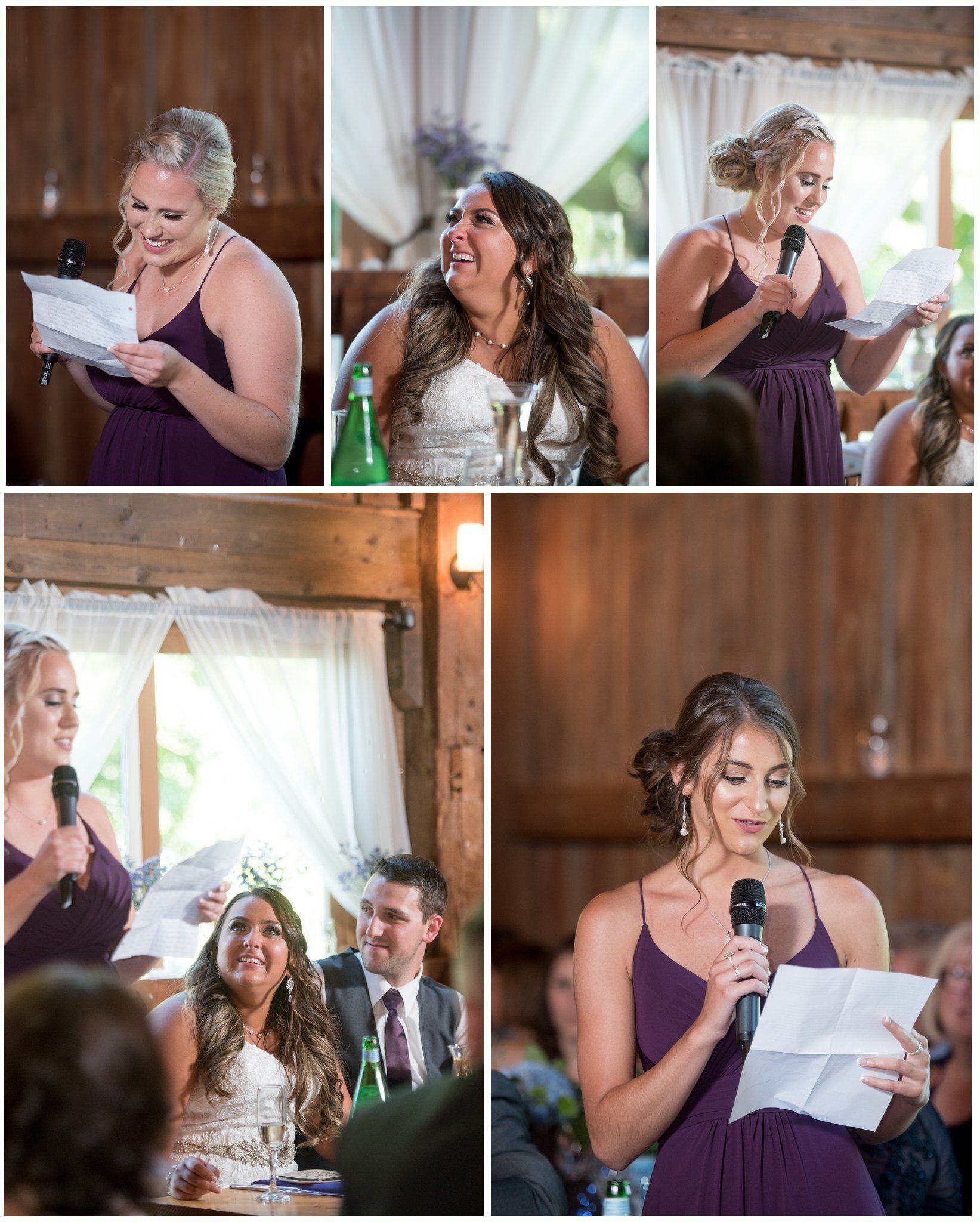 Woman reading from a paper and speaking into a microphone at a rustic indoor event, with guests seated nearby