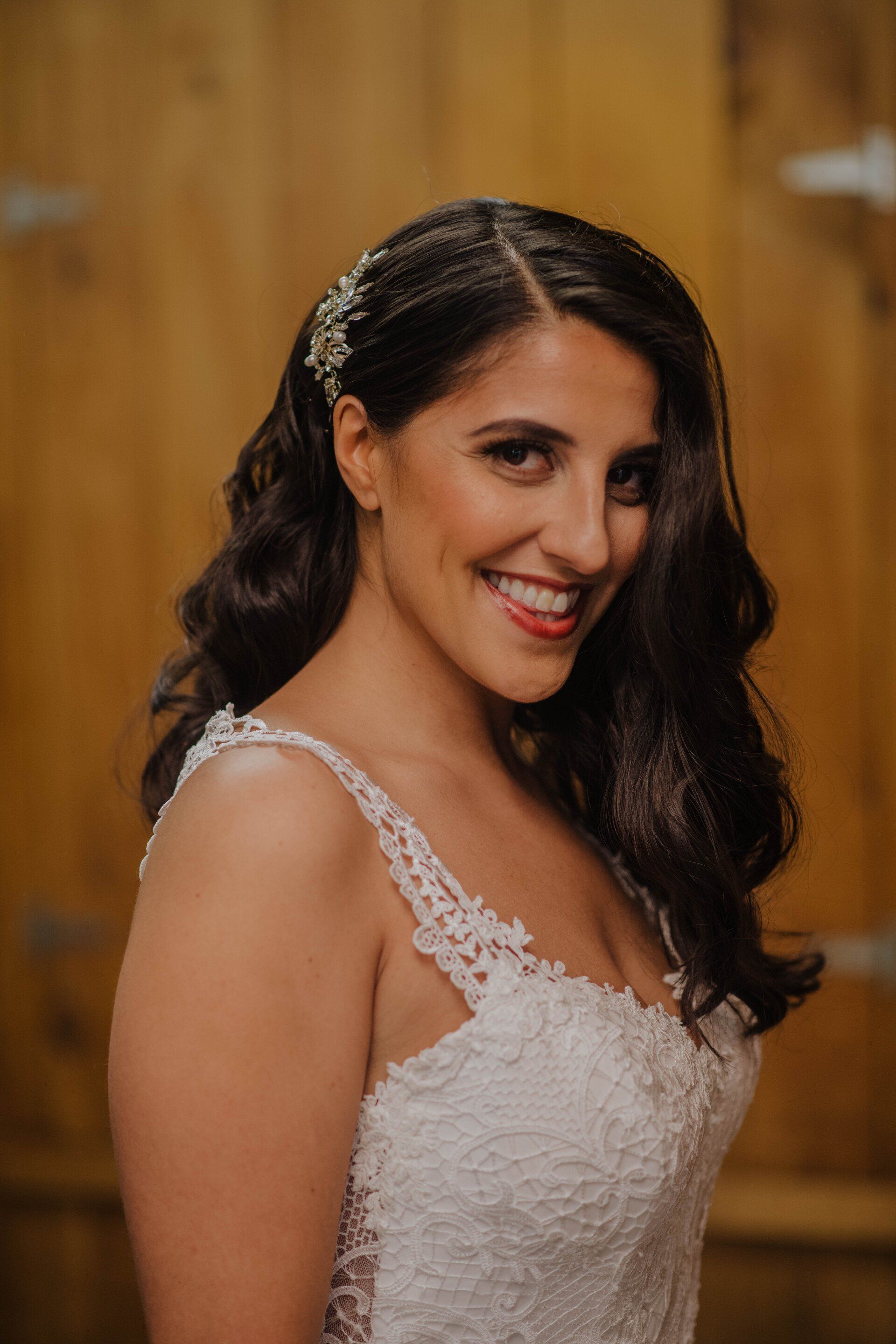 Woman in a white lace dress smiling in a wooden indoor setting