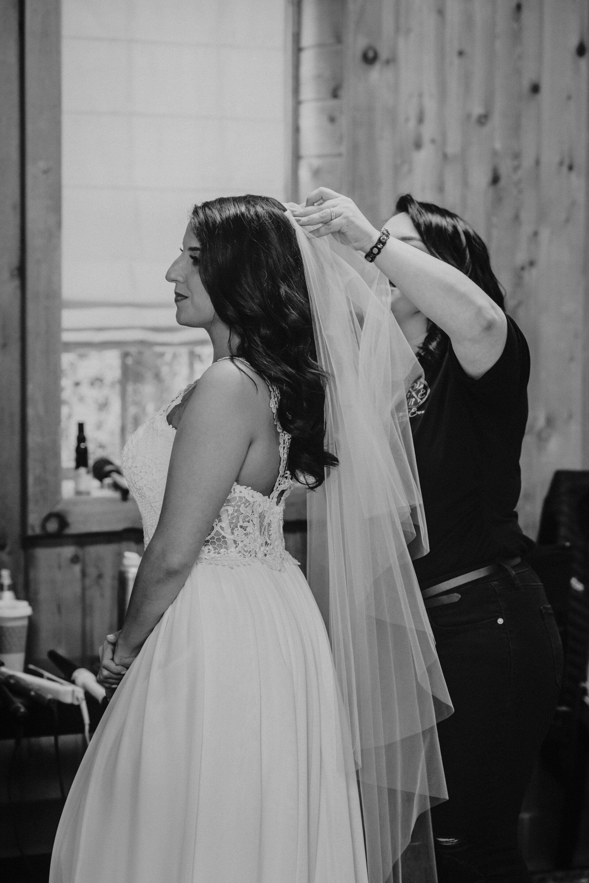 Bride being fitted with a veil by a stylist in a black-and-white room