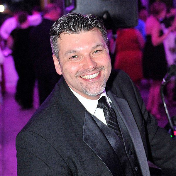 Smiling man in a dark suit at a purple-lit event