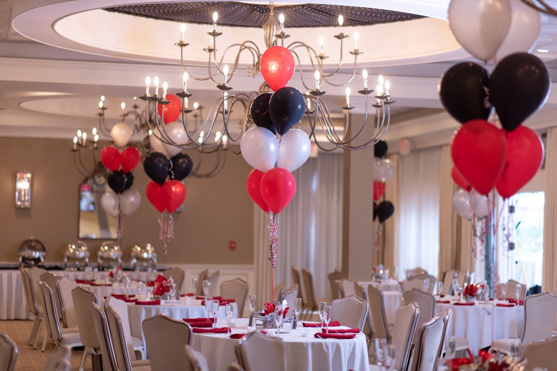 Balloon-decorated banquet hall with round tables set for an elegant party