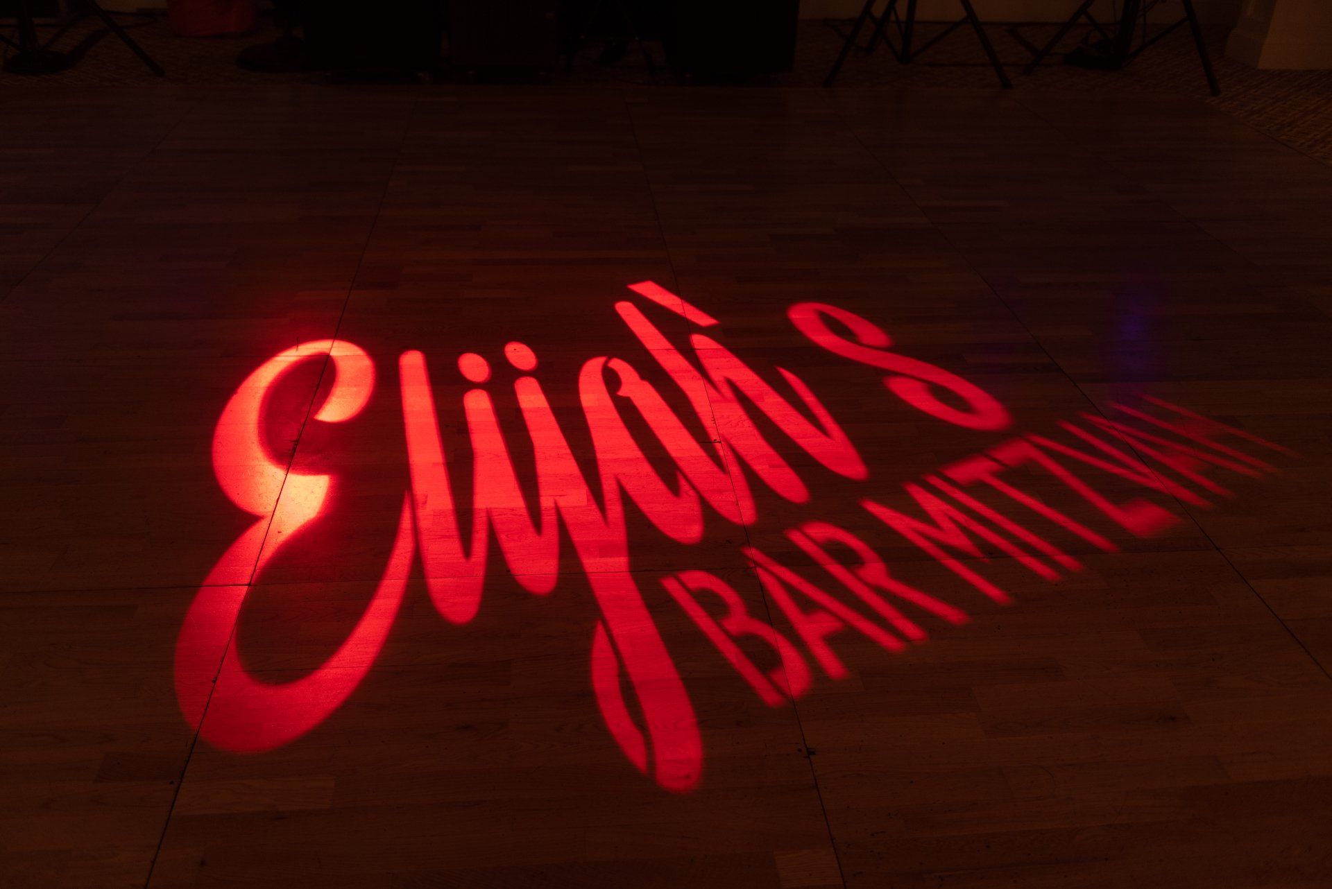 Red neon sign reading “Elliot’s Bartending” glowing on a dark floor.