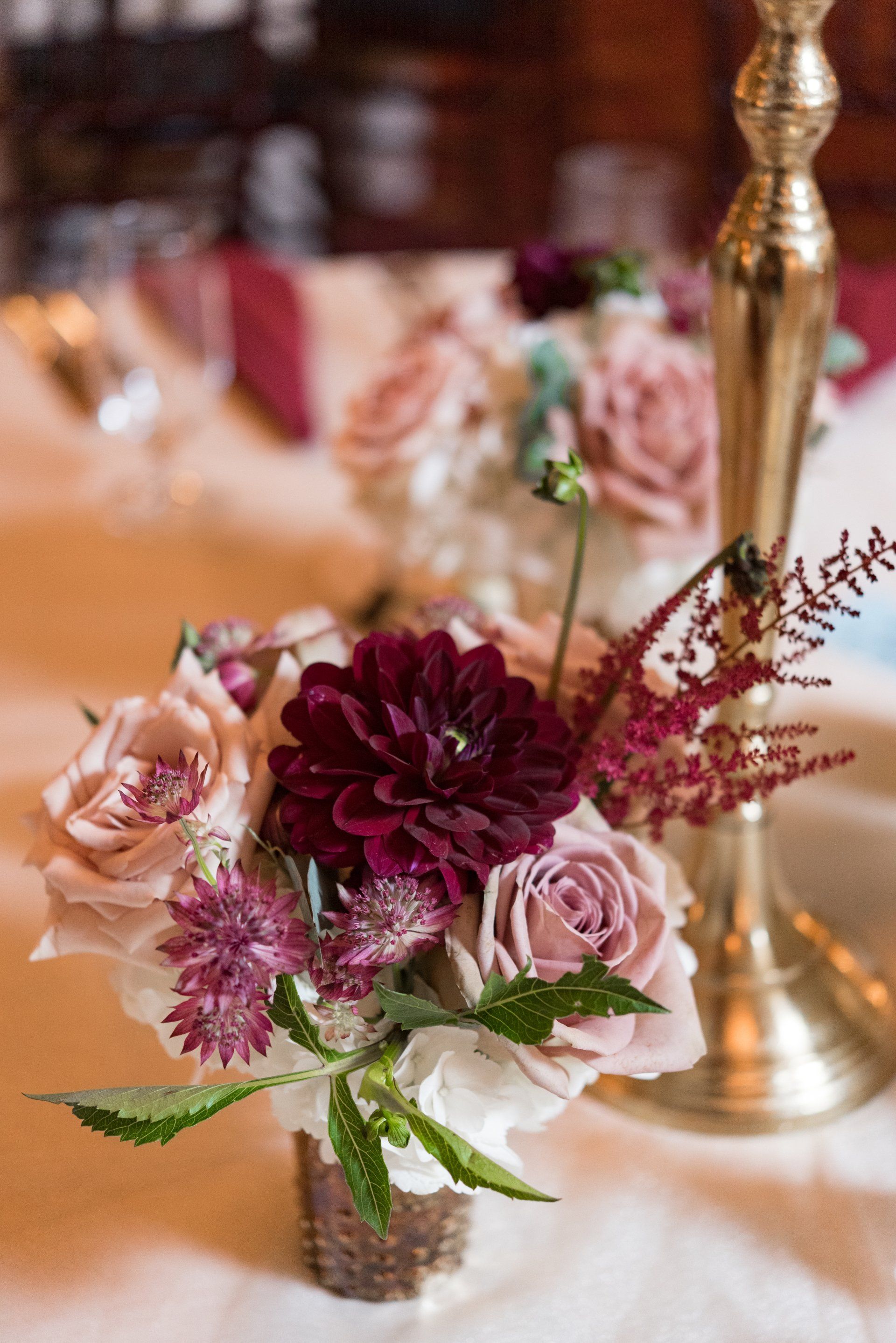 Pink and burgundy floral centerpiece in a small vase on a decorated table