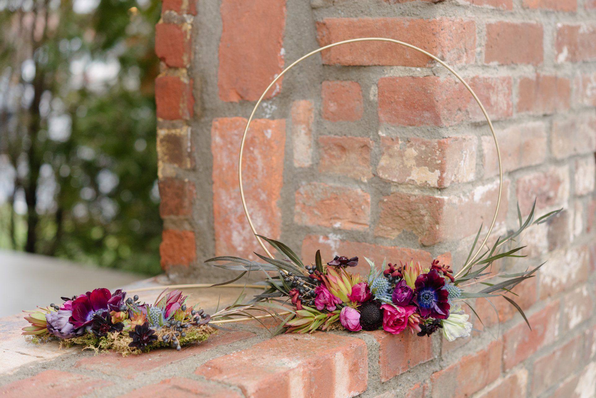 Bouquet of purple and pink flowers on a brick wall beside a circular mirror outdoors
