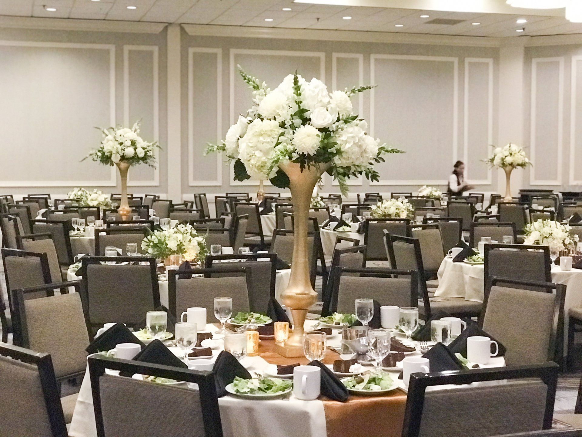 Elegant banquet hall with round tables set for an event and white floral centerpieces