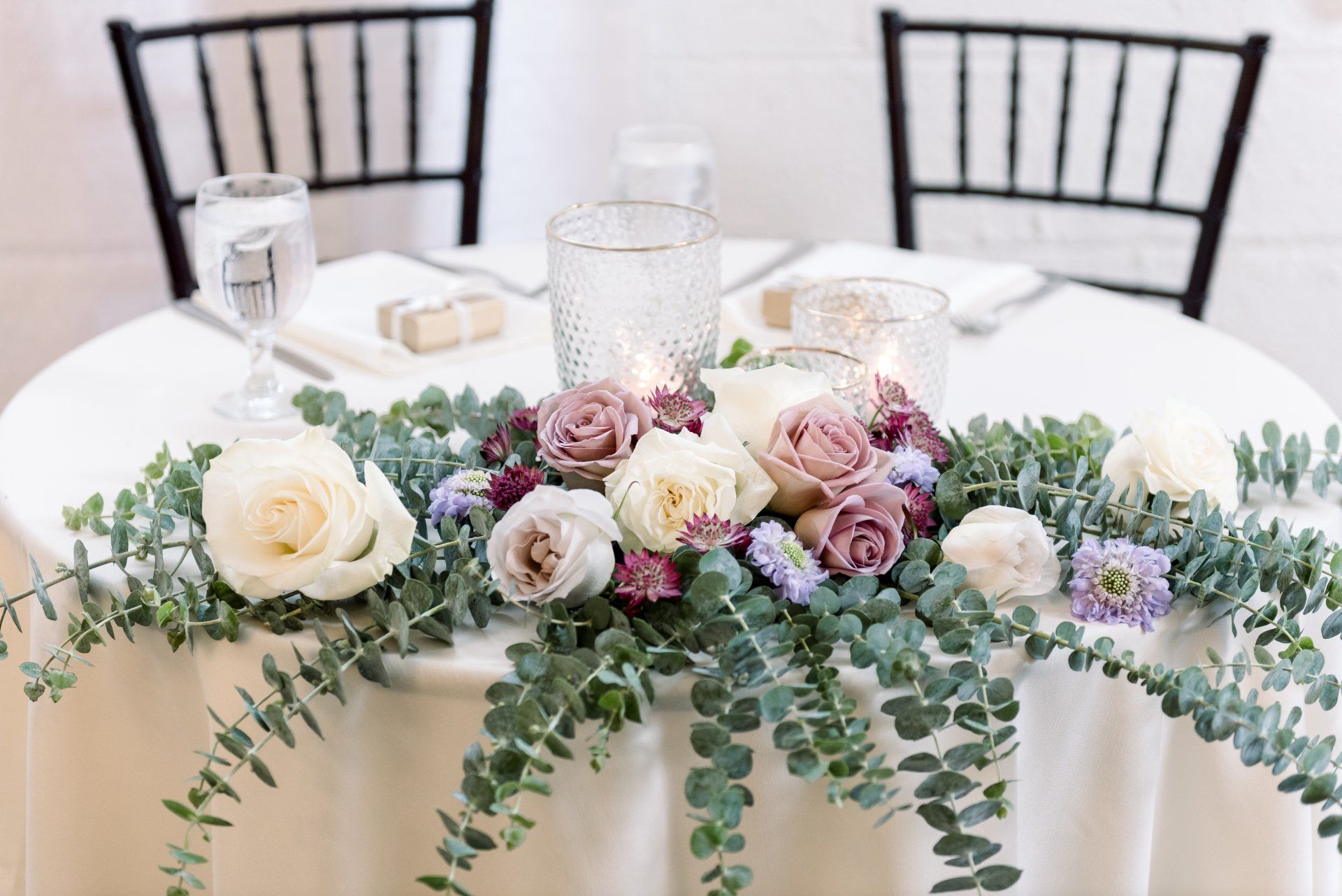 Round table with white cloth and pastel floral centerpiece in a bright dining setting