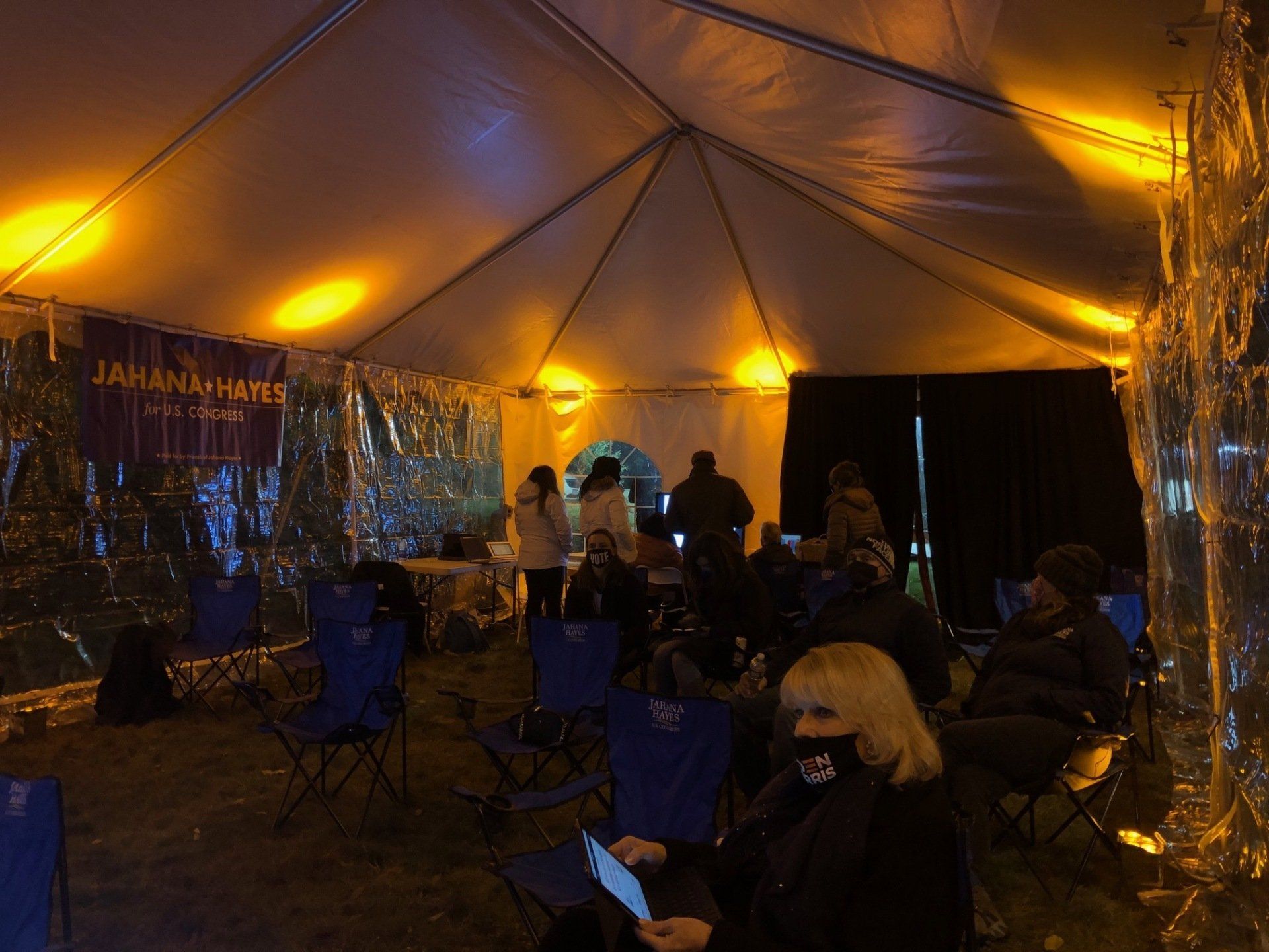 People seated inside a warmly lit tent at an evening gathering