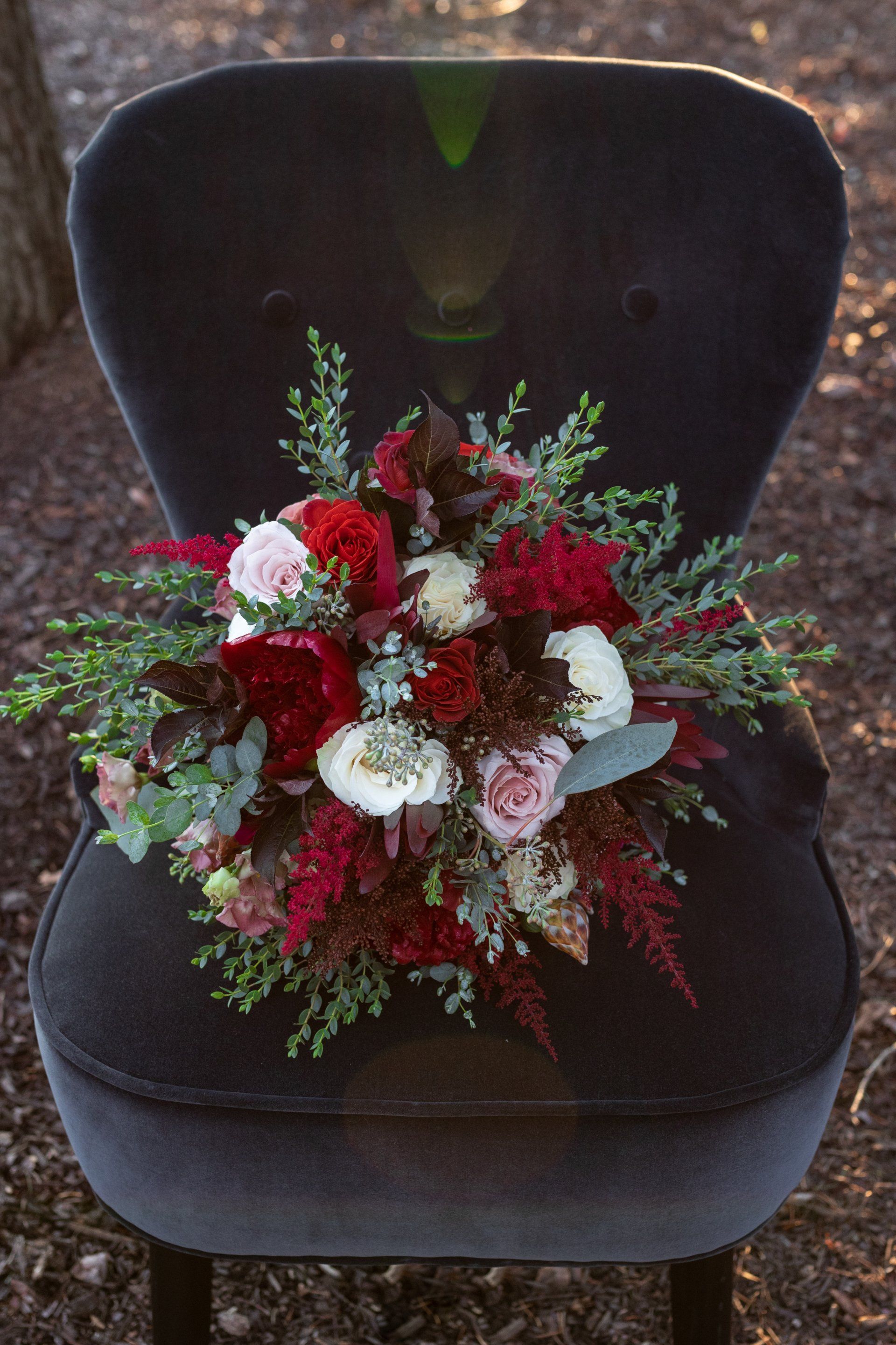 Red and white funeral flower arrangement on a dark chair outdoors