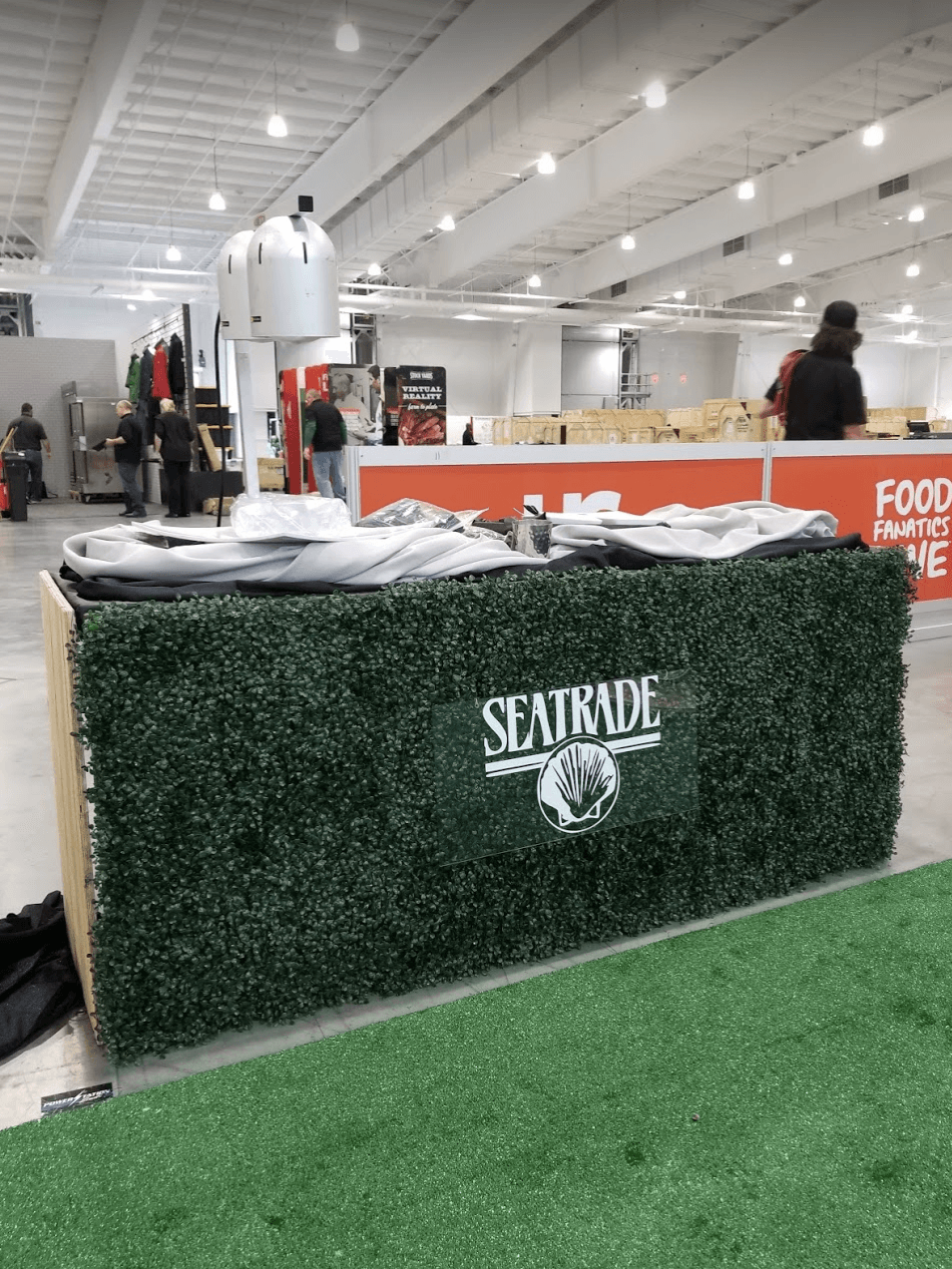 Indoor trade show booth with green hedge counter, Seattle sign, and people in a bright exhibition hall