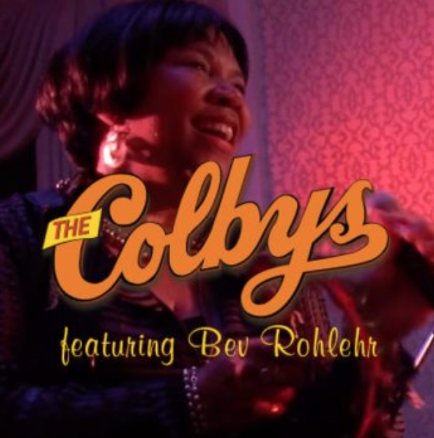 The Colbys title card with Bev Rohlehr on a pink-purple background