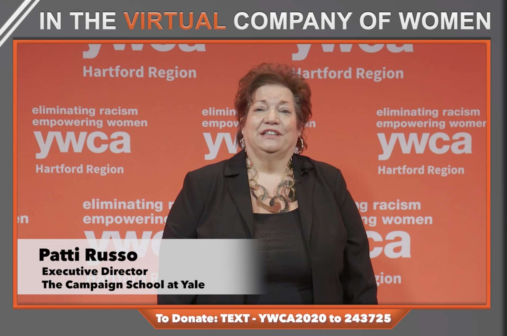 Patri Russo speaking at a Hartford Region YWCA event with orange backdrop and campaign signage