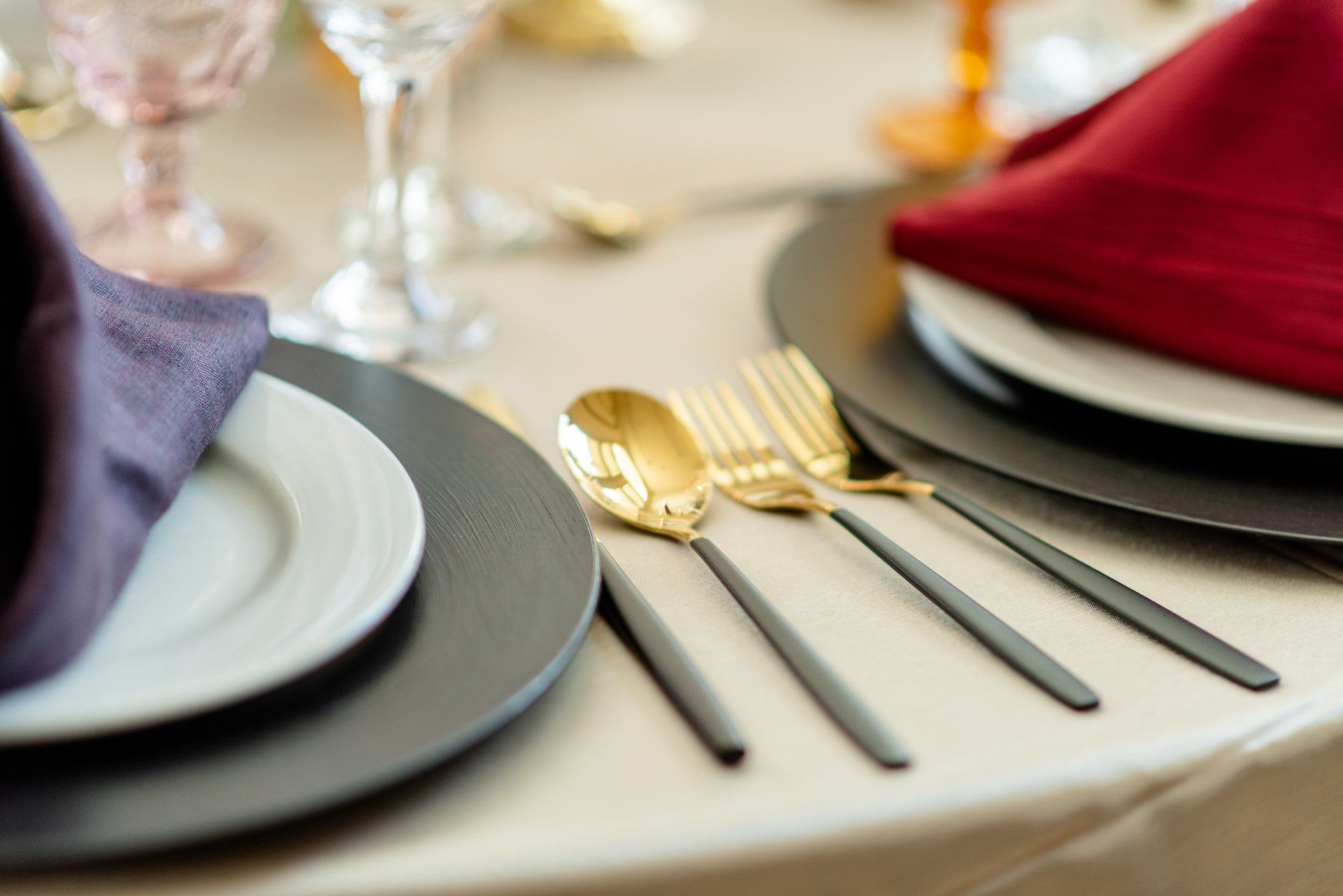 Elegant table setting with gold forks and silverware beside gray plates and folded napkins