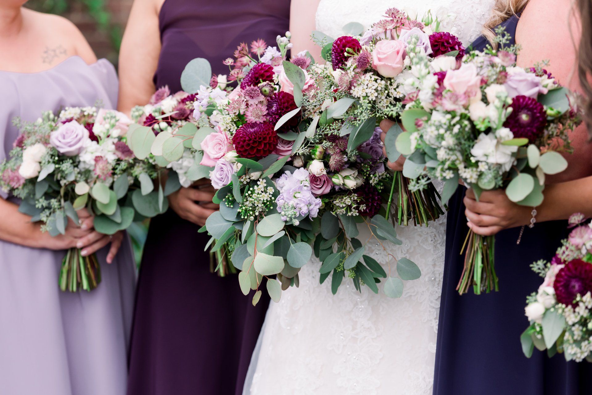 Bridesmaids holding pastel bouquets beside a bride in a white dress and lavender dresses