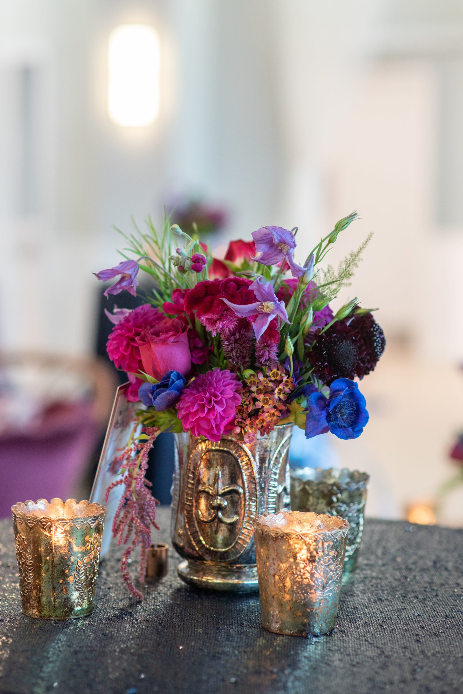 Floral arrangement in a silver face vase with candles on a table