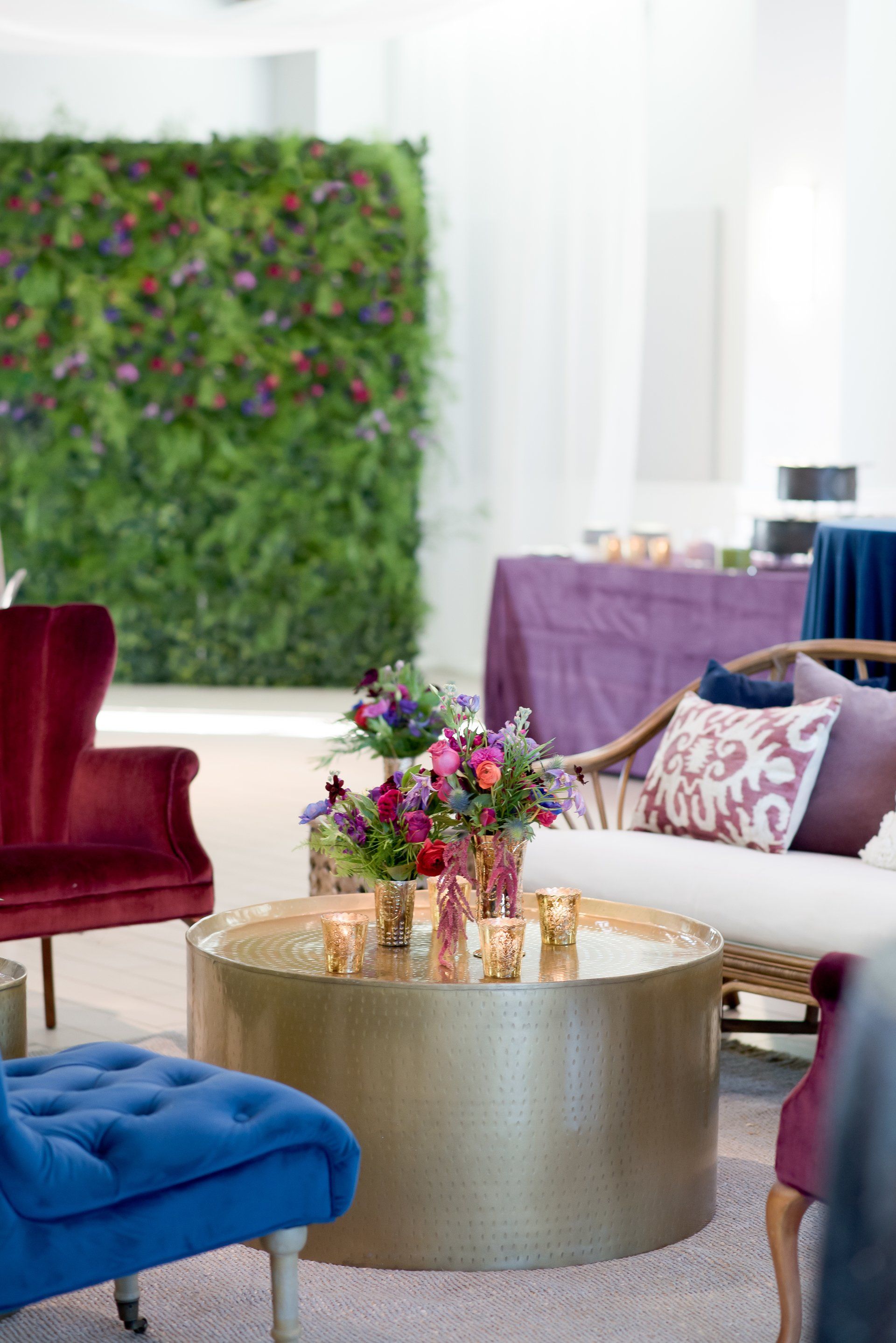 Colorful lounge with velvet chairs, gold coffee table, and green floral wall decor