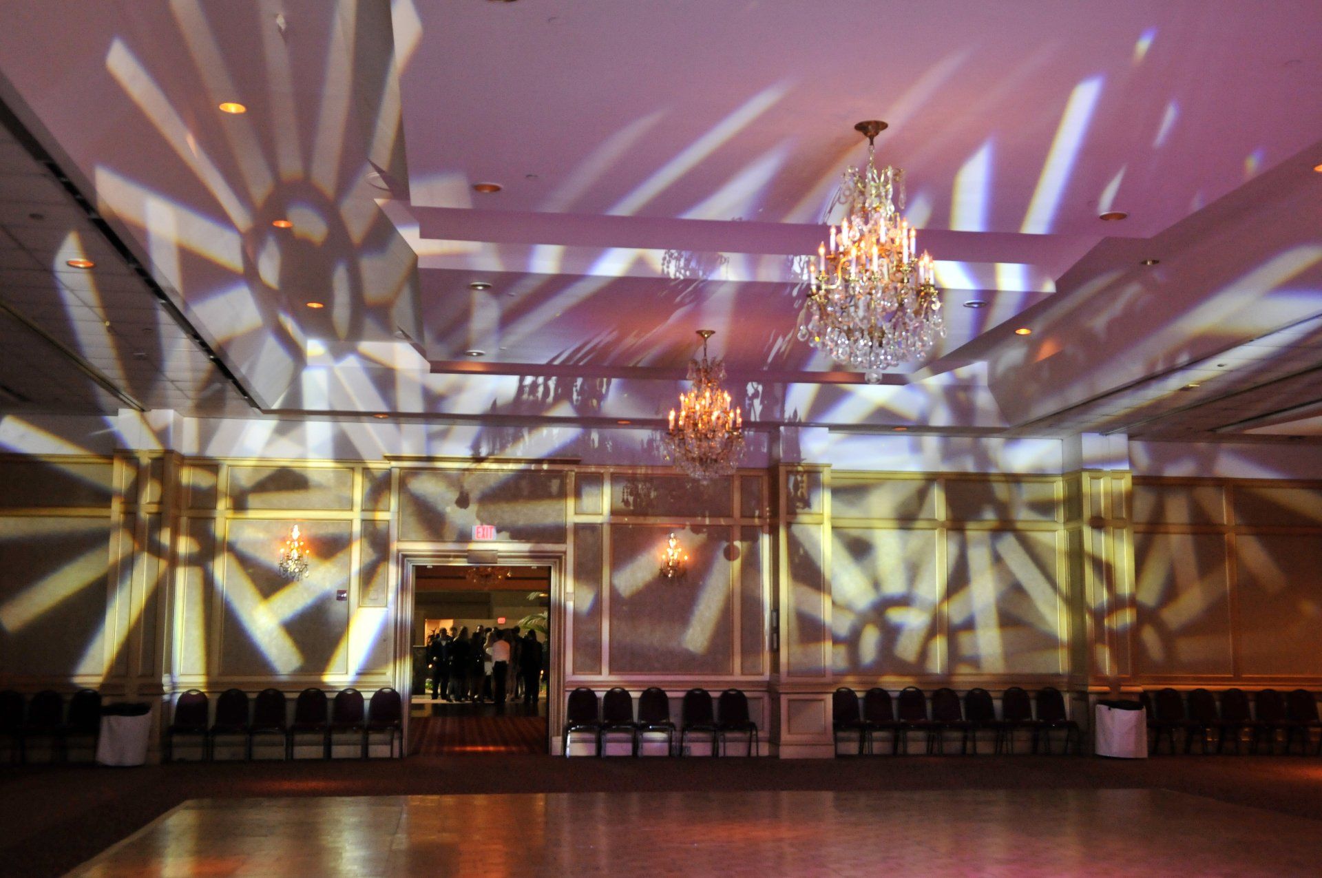 Empty banquet hall with chandeliers and patterned light projections on the walls and floor