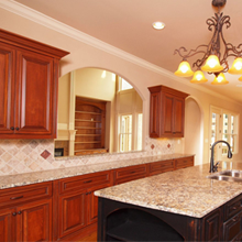 A high-end kitchen with wooden cabinets, granite countertops, an island, a stone backsplash, and an arched wall opening.