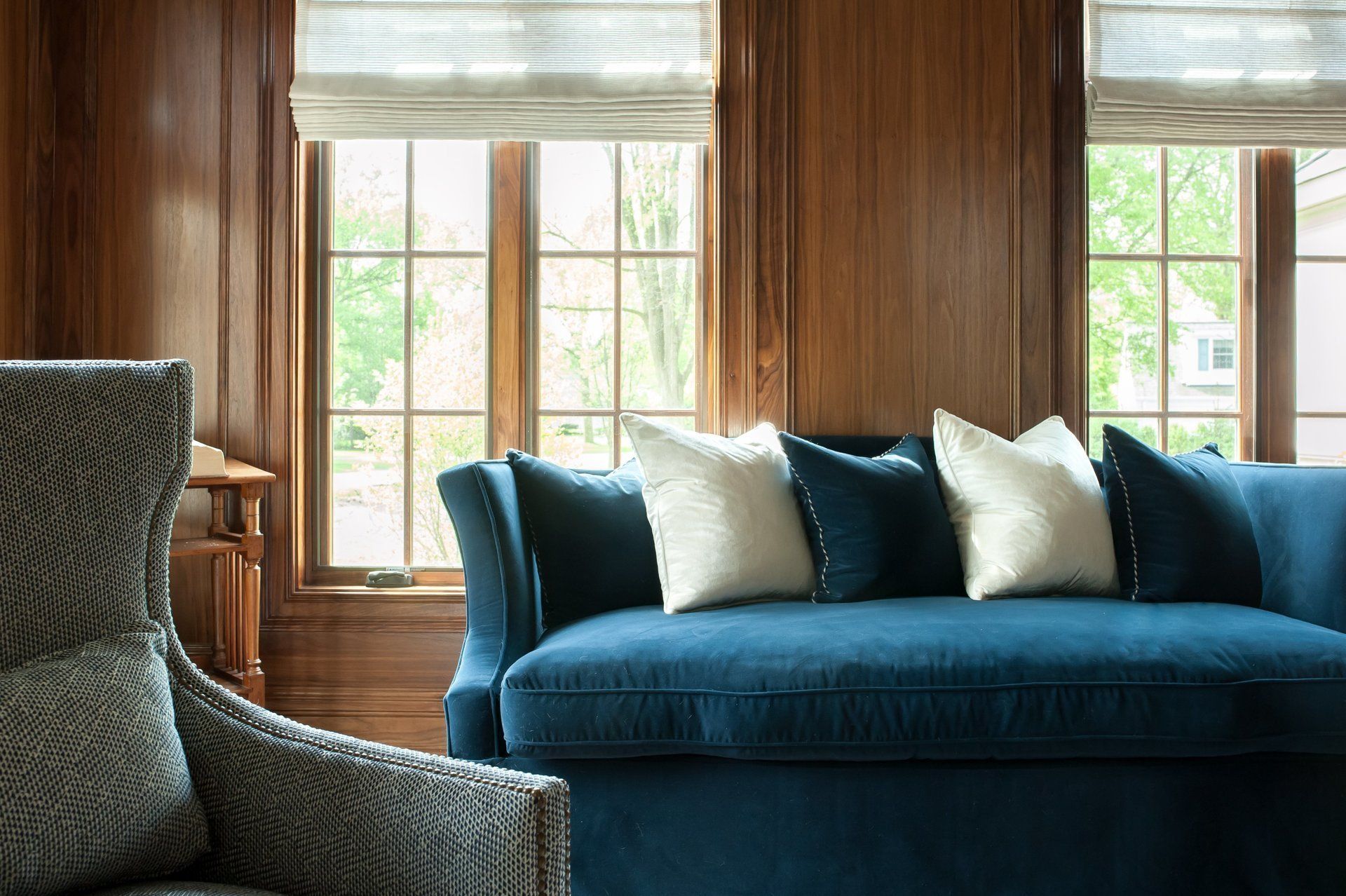 A living room with a blue couch , chair , and windows.