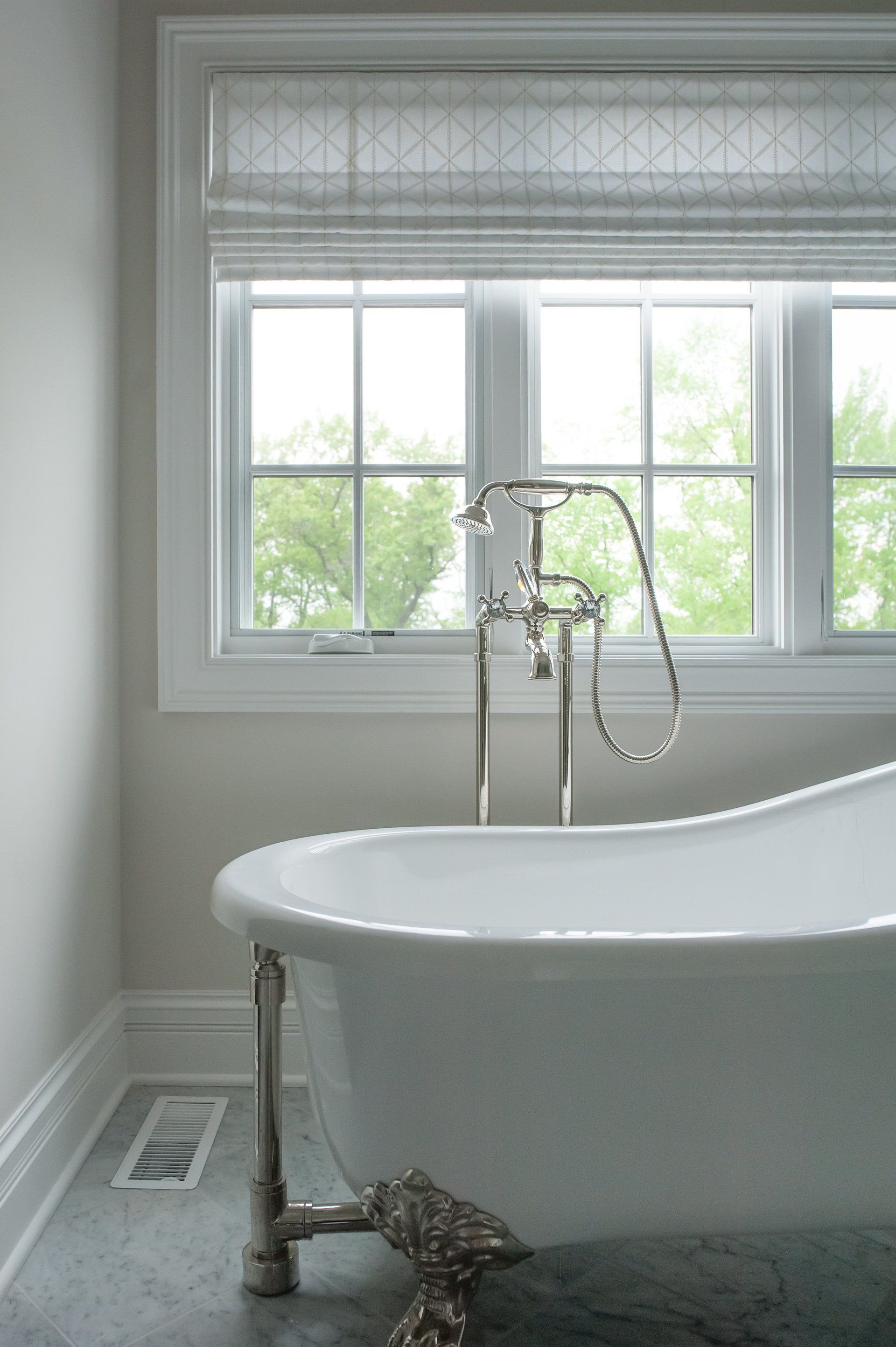 A bathroom with a claw foot tub and a window.