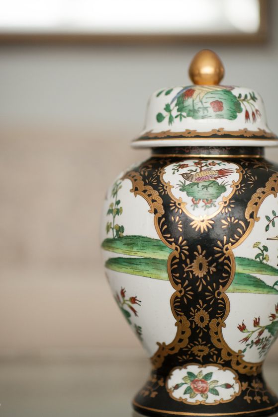 A black and white vase with a lid is sitting on a table.