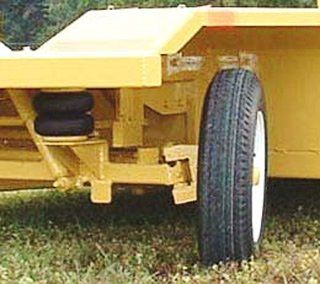 Yellow trailer wheel with a black air suspension and tire on grass.