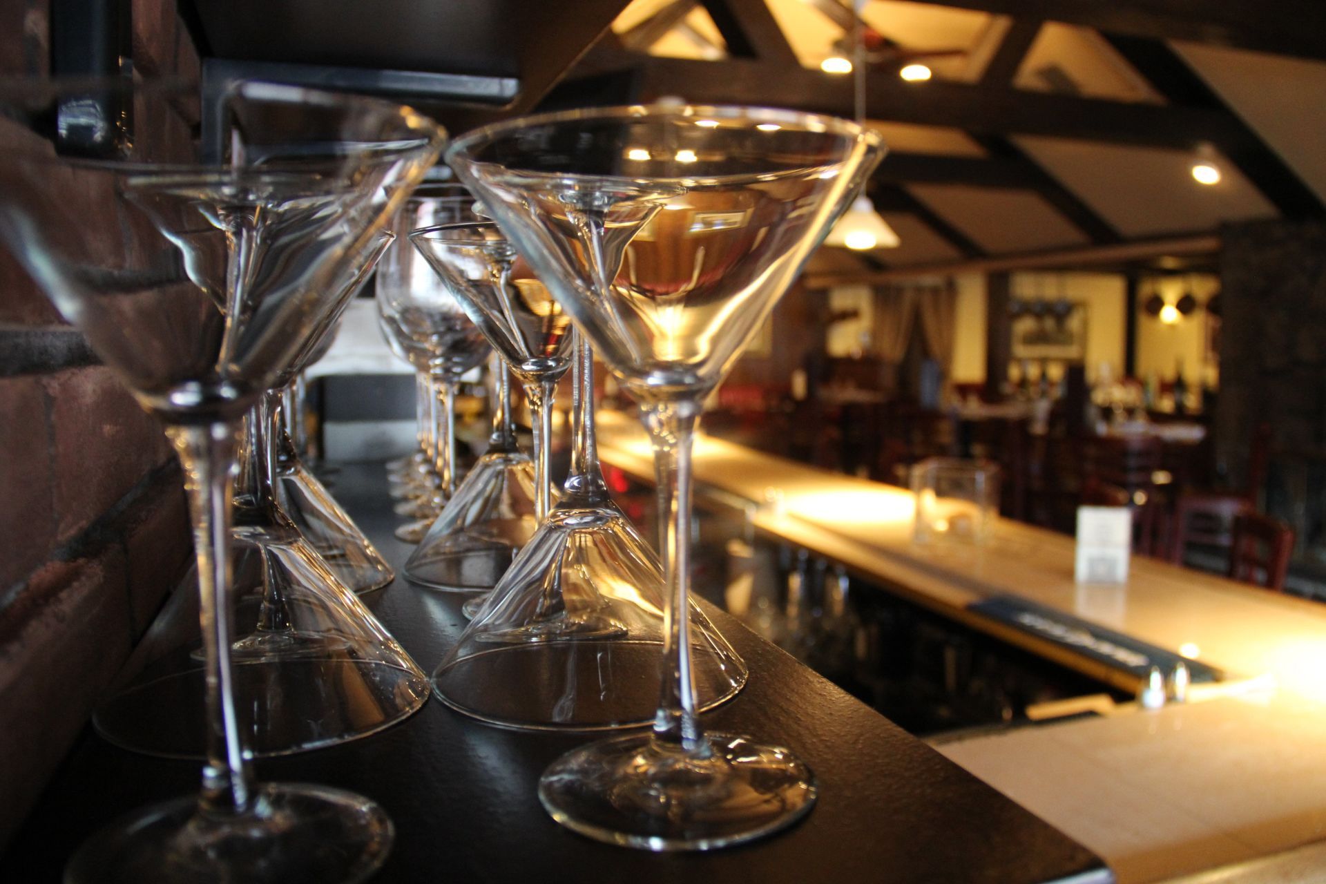A row of martini glasses on a bar in a restaurant