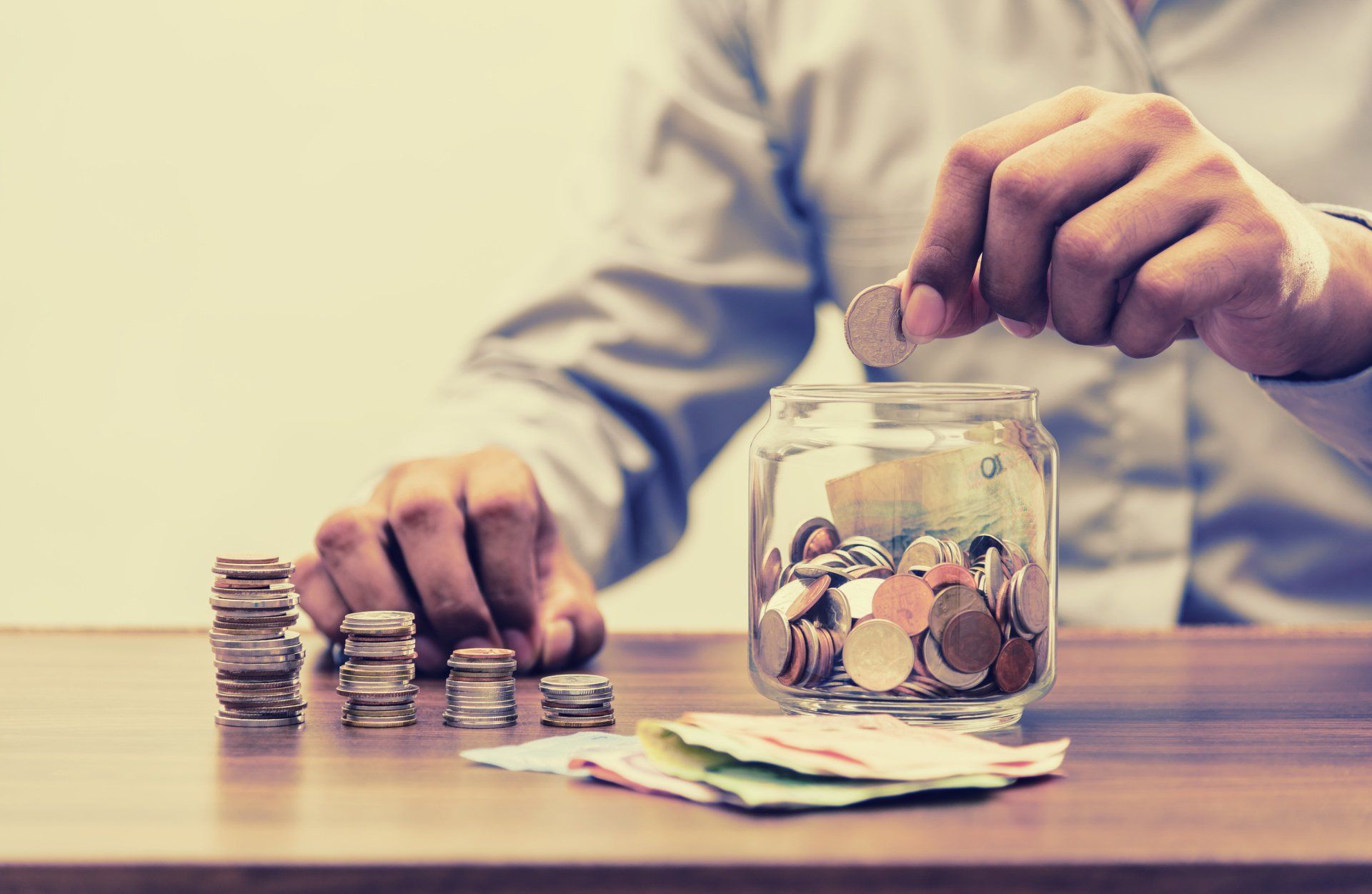 man hand putting coins in the jar