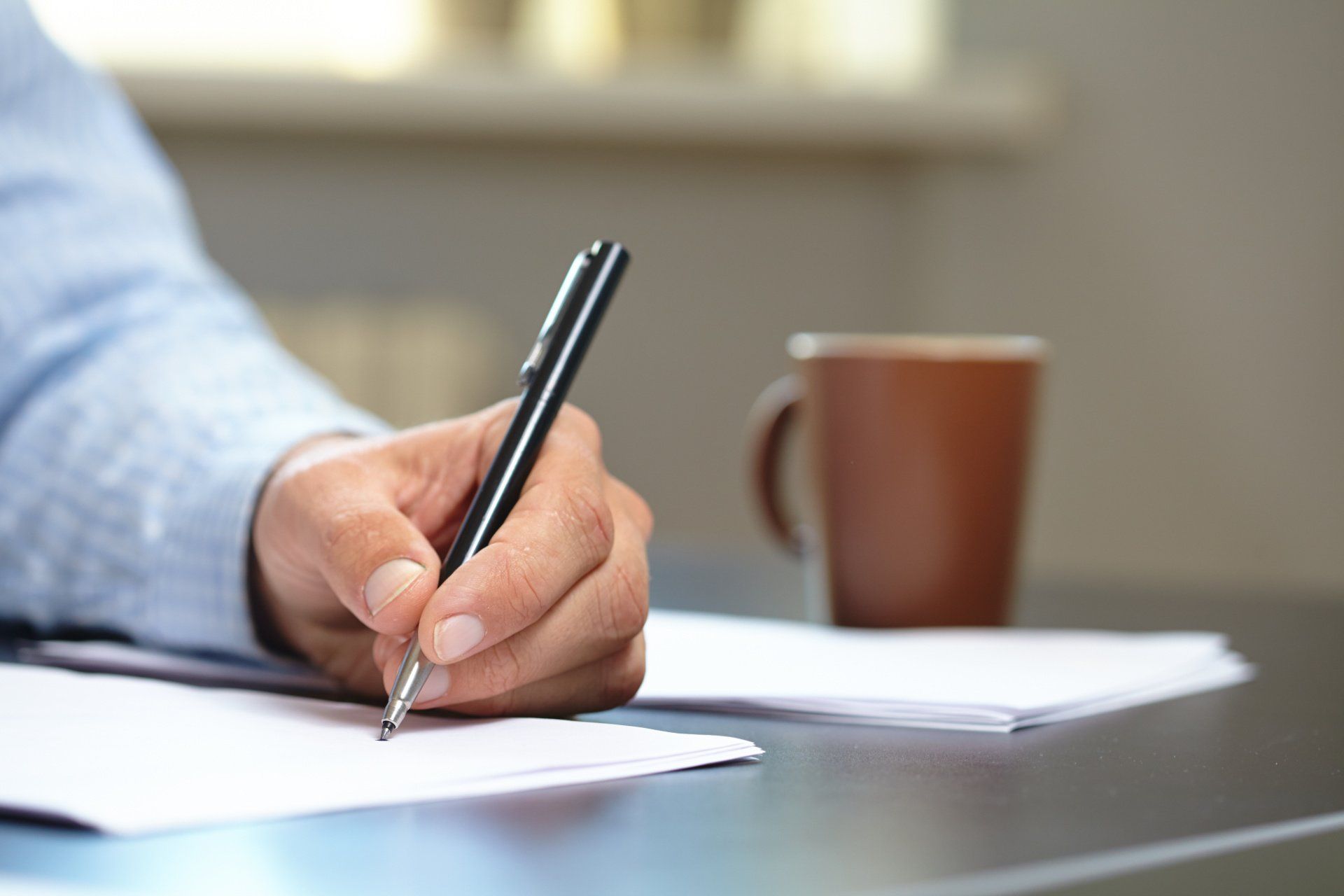 man in blue shirt with pen ad paper