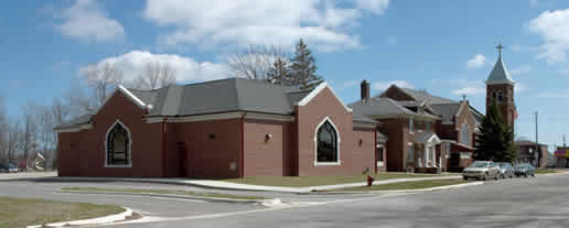 A brick church with a steeple and a fire hydrant in front of it