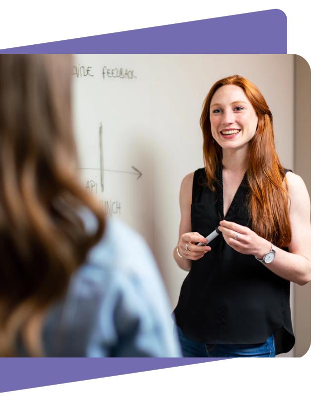Woman talking to other woman in front of white board