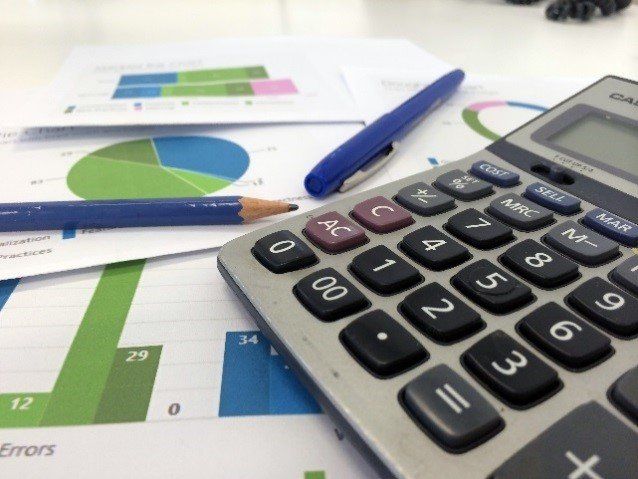 Calculator, pens, and charts with graphs on a desk, representing financial data and analysis.