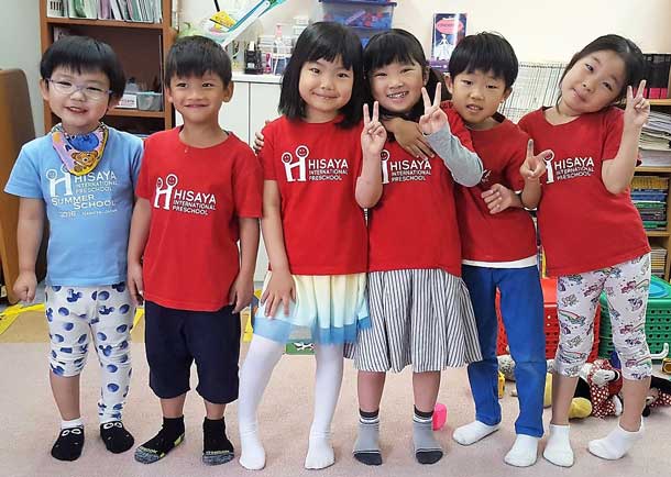 カラフルなシャツを着て、笑顔でピースサインをしている6人の子供たちの写真