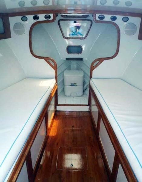 The inside of a boat with two beds and a toilet