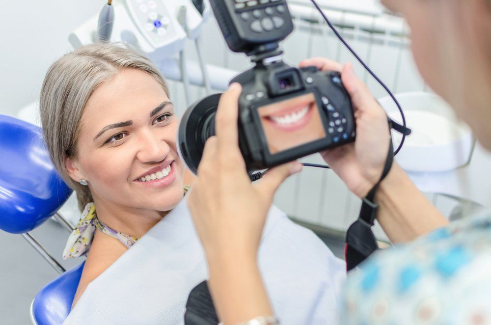 Patient smiling while a dentist takes a close-up photo in a dental clinic