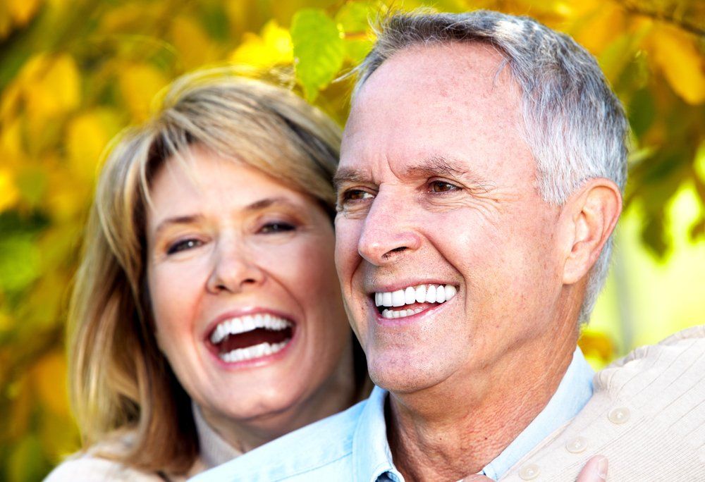 Smiling couple outdoors with green leaves in the background