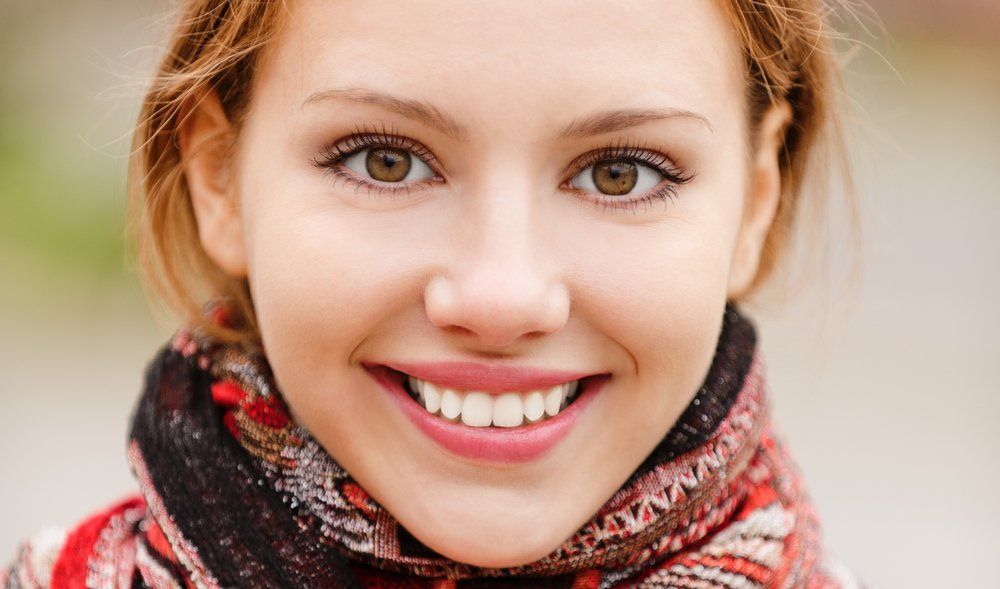 Smiling woman in a red-and-black scarf, close-up portrait outdoors