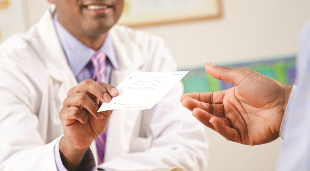 Doctor handing a prescription to a patient. Doctor handing a prescription to a patient.