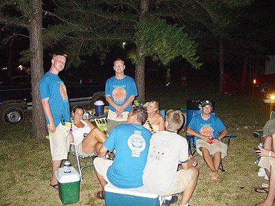 A group of people are sitting around a cooler in the grass