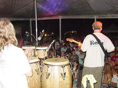 A man wearing a shirt that says Relix playing a guitar in front of a crowd