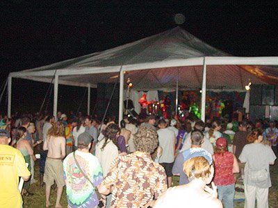 A crowd of people are gathered under a tent at night