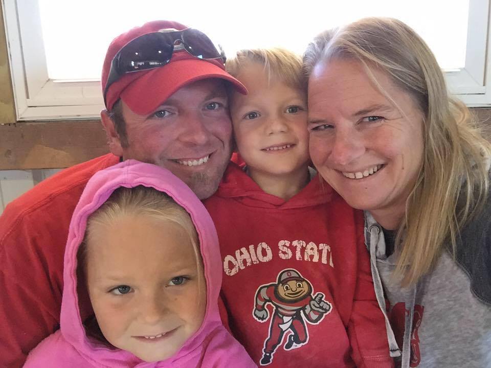 A man and woman are posing for a picture with two children wearing ohio state sweatshirts.