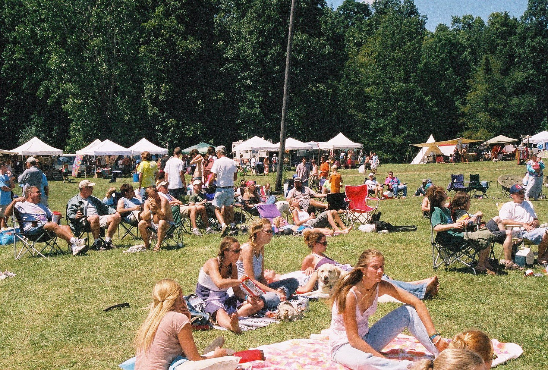 A group of people are sitting on blankets in a grassy field