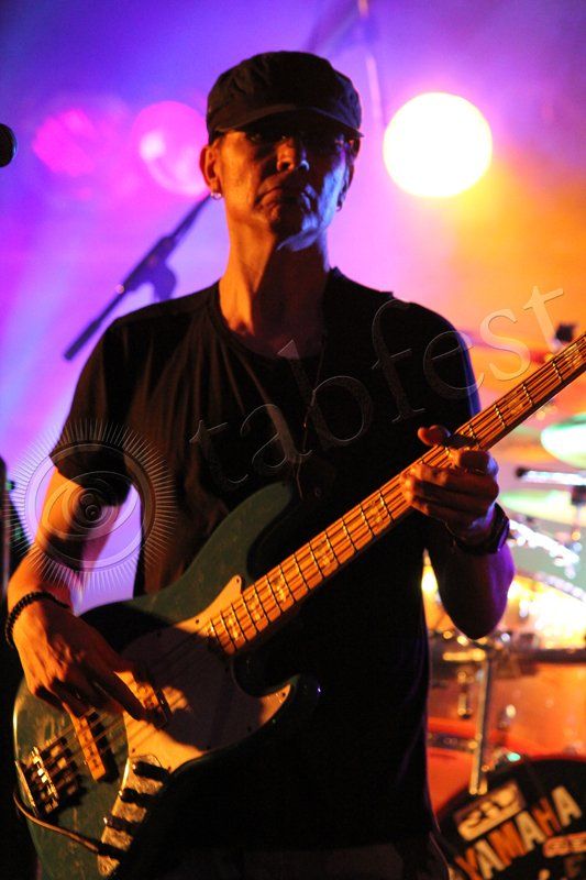 A man is playing a guitar on stage in front of a microphone. This man is Freekbass.