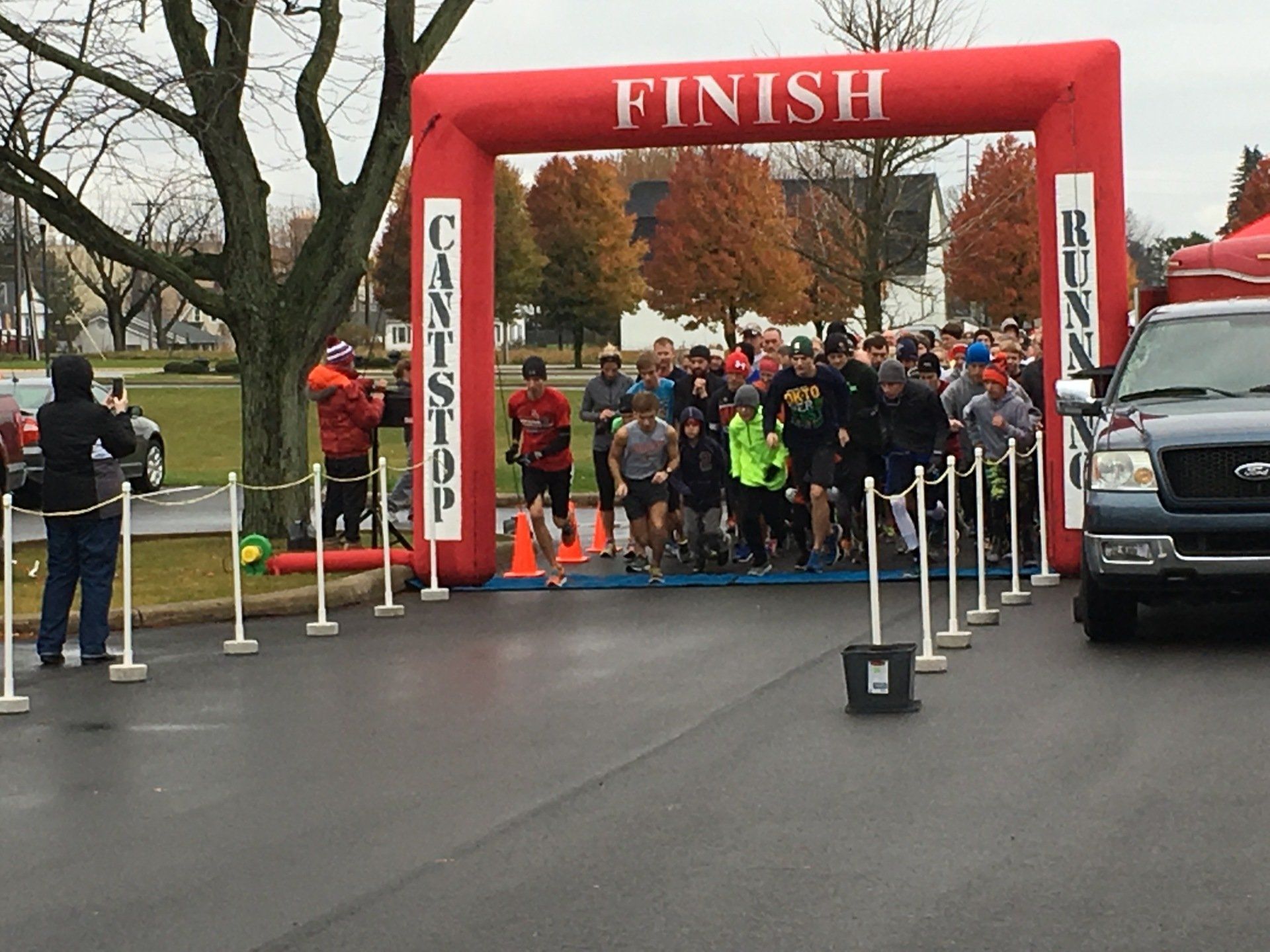A group of people are running under a red finish sign getting ready to start the Harmony for Ohio Foundation Turkey Trot.