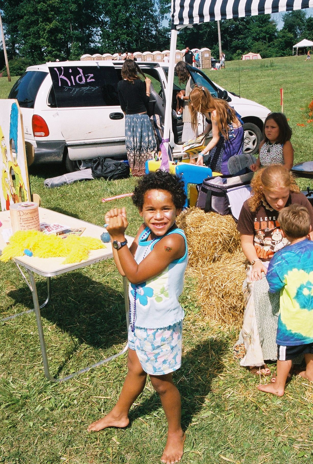 A little girl is standing in front of a table with the word kids on it.