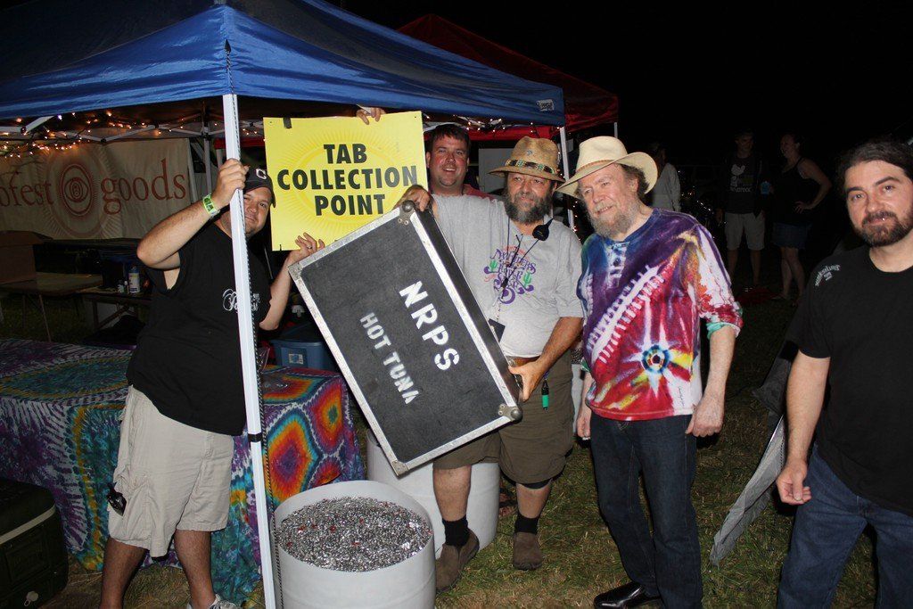 A group of men, the New Riders of the Purple Sage, holding a sign that says tab collection point