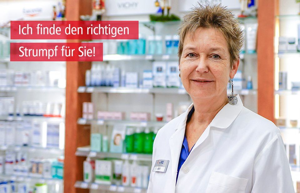 Eine Frau im weißen Kittel steht in einer Apotheke.