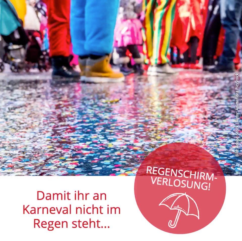 Eine Gruppe von Menschen in bunten Kostümen steht auf einem nassen, mit Konfetti bedeckten Boden.